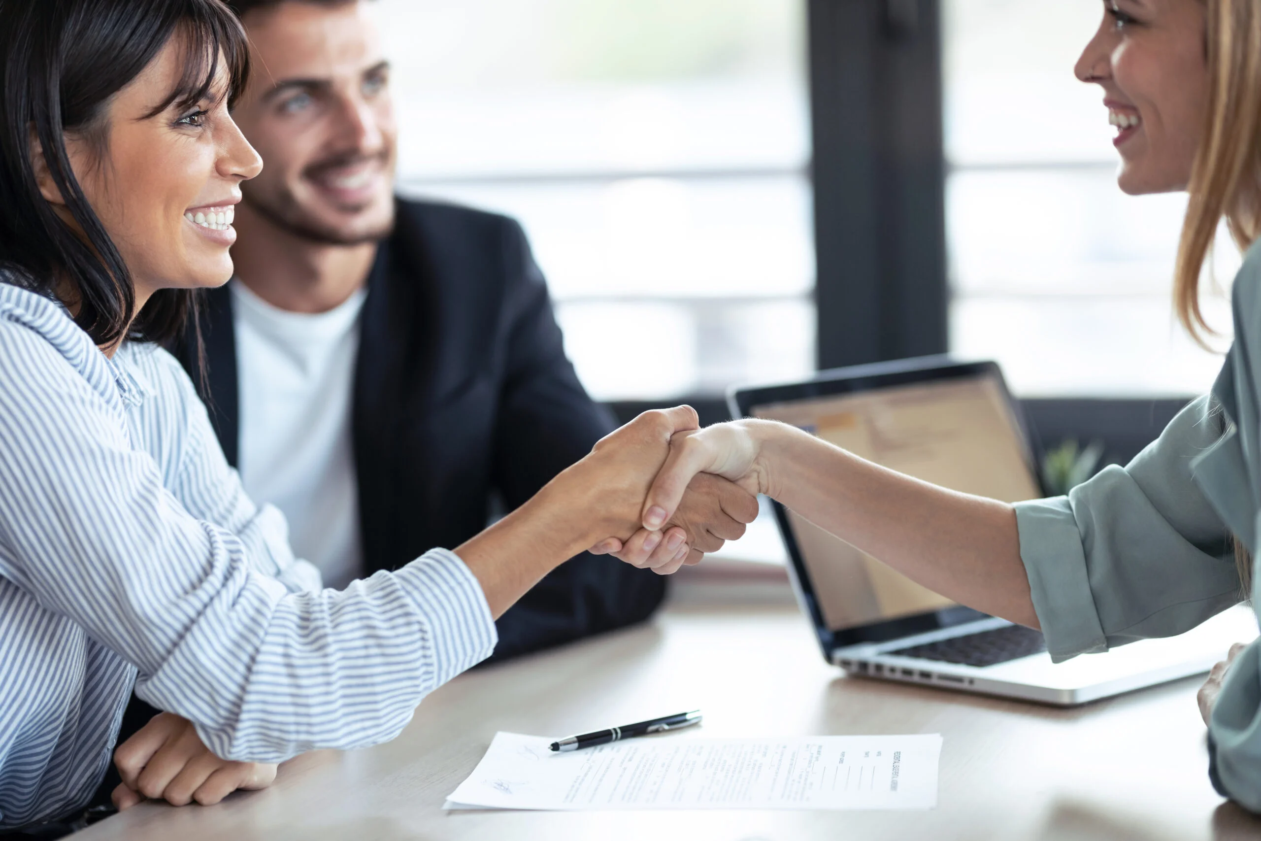 Attractive real-estate agent shaking hands with young couple
